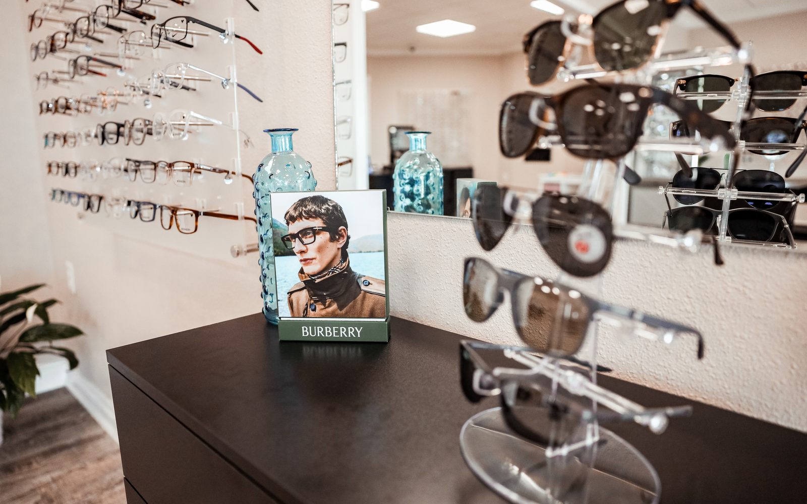 Burberry display vignette at Eye Koni Optical with sunglasses, framed campaign, and the designer frame wall